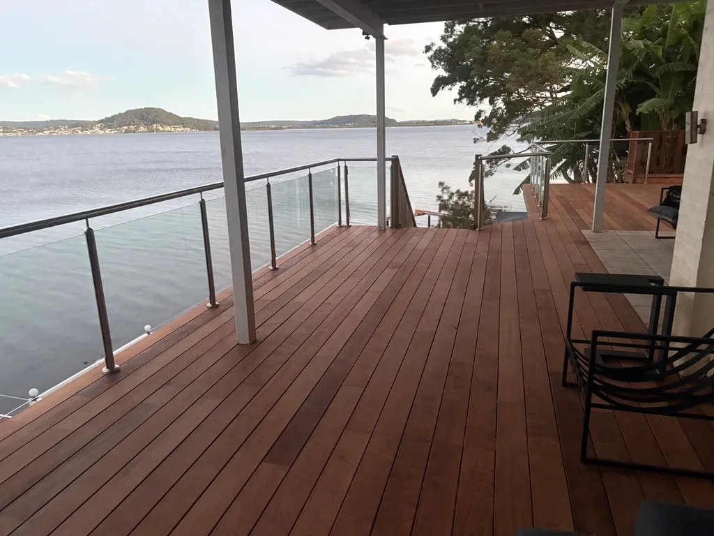 A merbau deck with a glass balustrade looking out over the water to a headland