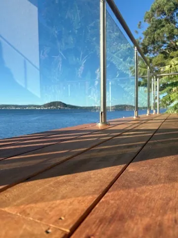 A frameless glass balustrade on a merbau deck with uninterrupted water views
