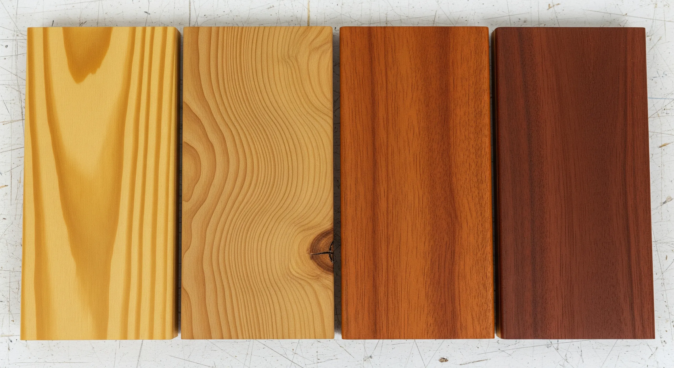 Four decking timber samples laid side by side, from pale blackbutt to deep red merbau