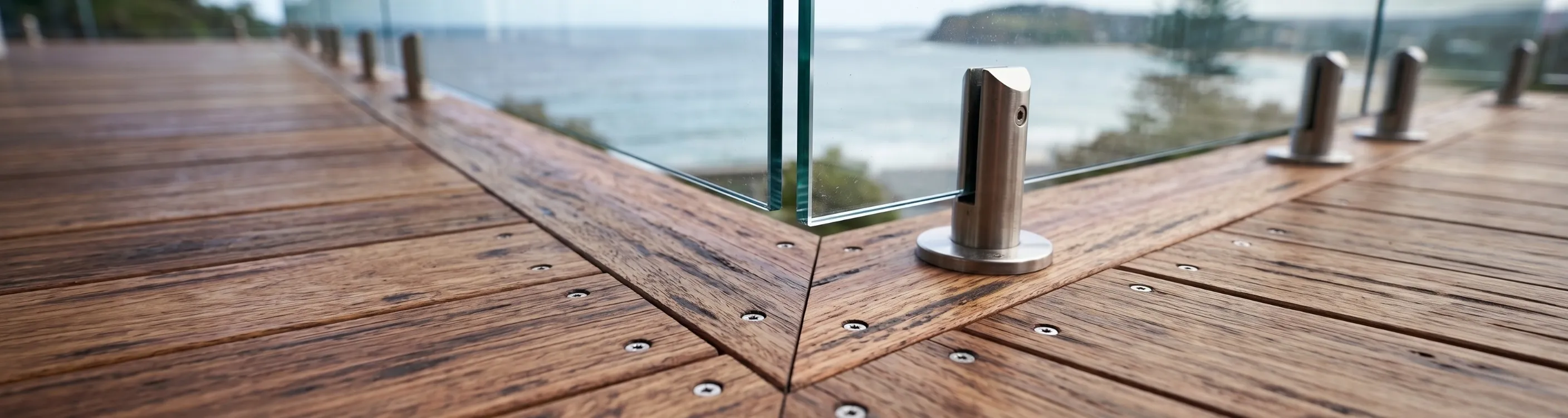 A spotted gum timber deck with frameless glass balustrades looking out over the water